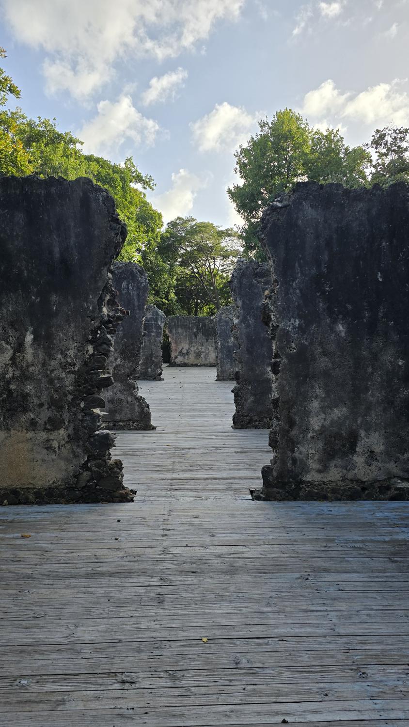 A wooden walkway between old stone ruins under a bright sky