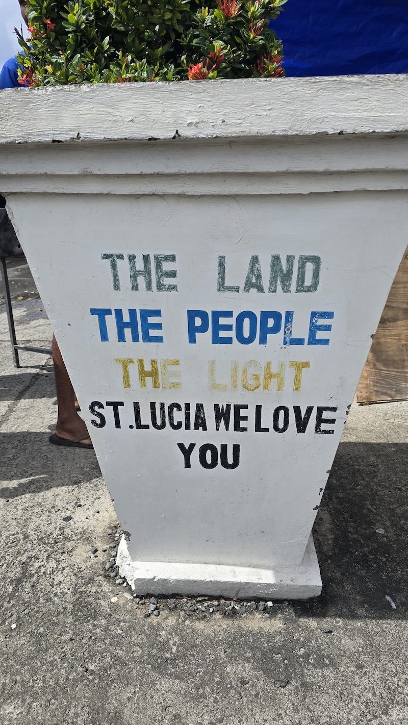 A painted roadside marker in Saint Lucia reading: The land, the people, the light. St Lucia, me love you.