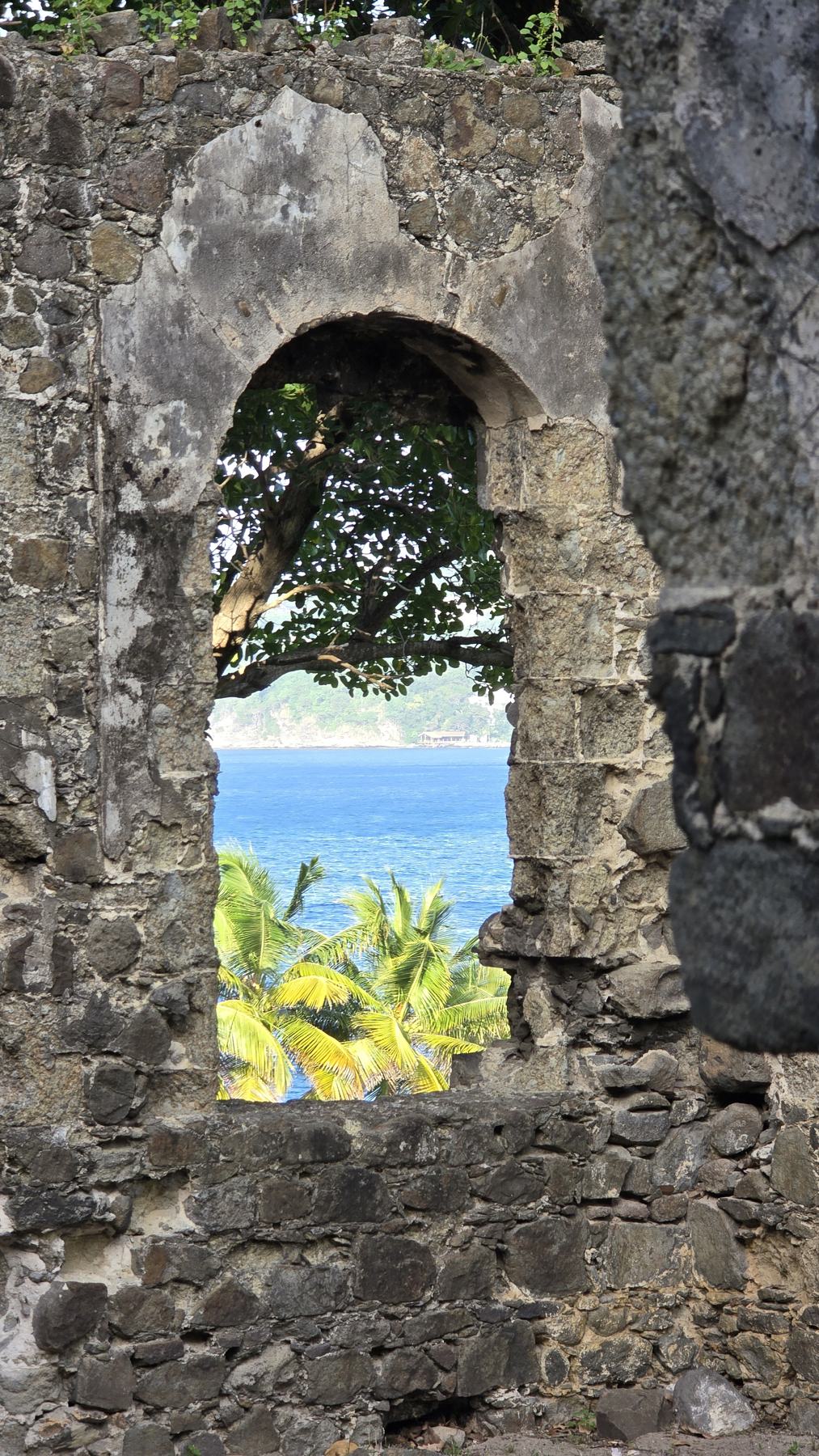 The sea seen through a window in an old stone wall